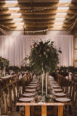Tall greenery arrangements on wooden trestle tables
