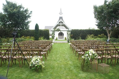 oak valley arch with wooden cross back chairs and white flowers