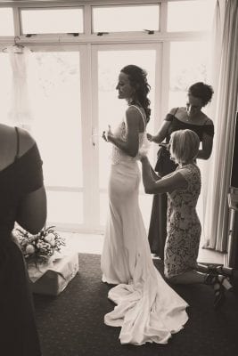 bride getting ready in front of window with bridal party