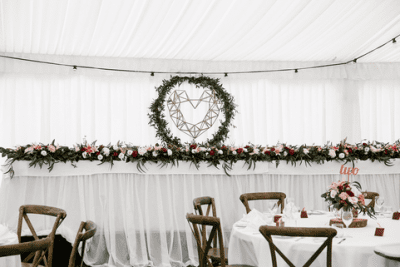 bridal table arrangement in burgundys and blush with geometric heart and festoon lights