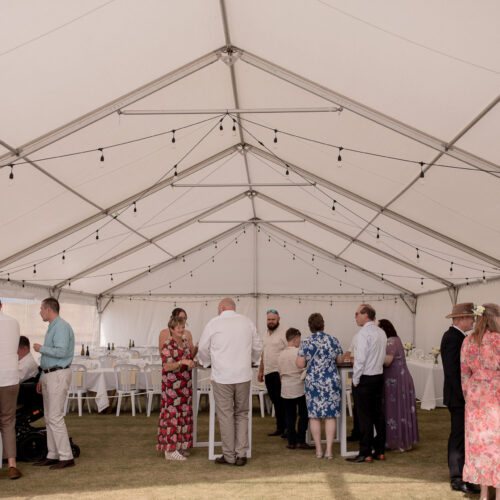White Marquee with wedding guests and festoon lighting